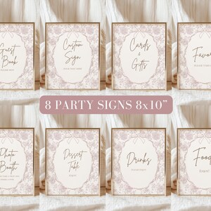 May include: Eight printable 8x10 inch party signs with a pink and white lace design. The signs include the text: Guest Book, Custom Sign, Cards & Gifts, Favors, Photo Booth, Dessert Table, Drinks, and Food.