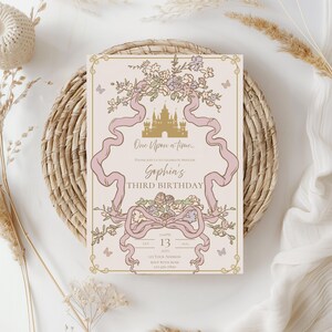 K&ouml;nnte beinhalten: Eine hellrosa Geburtstagseinladung mit floralen und Bandakzenten. Die Einladung tr&auml;gt den Text "One Upon a time... Sophia's Third Birthday" und enth&auml;lt Datum, Uhrzeit und Adresse.