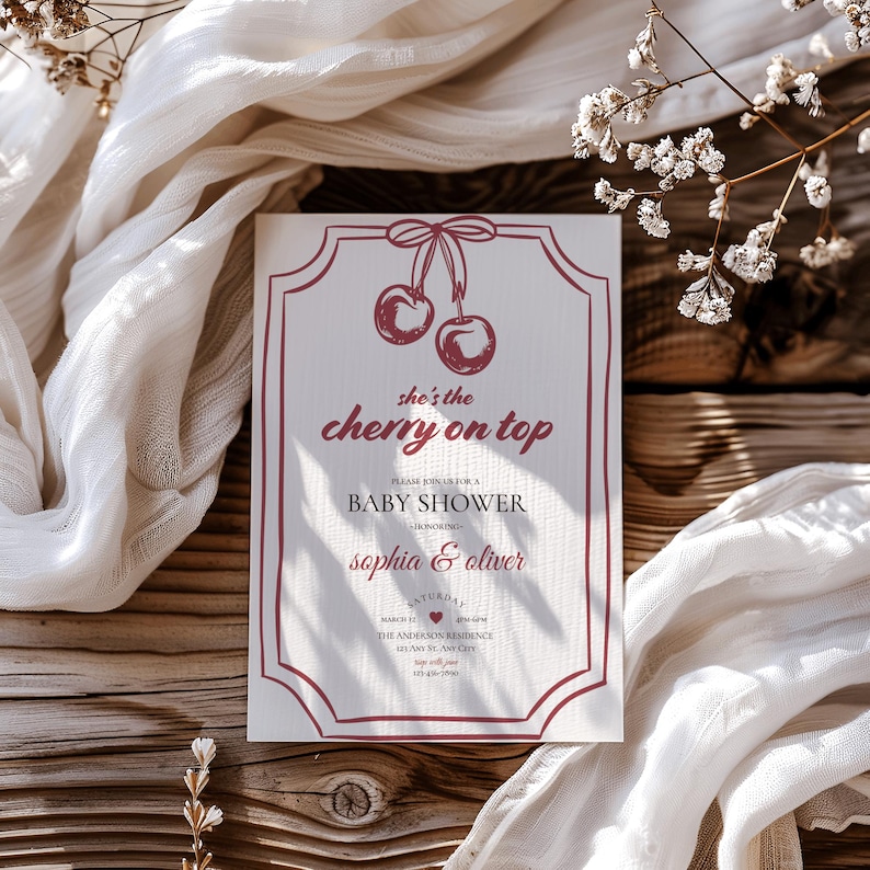 Op de afbeelding: Een rode en witte babyborrel uitnodiging met een kerstillustratie en de tekst "she's the cherry on top". De uitnodiging is voor een babyborrel ter ere van Sophia & Oliver.