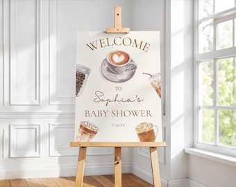 May include: A welcome sign for Sophia's baby shower, featuring coffee-themed illustrations. The sign includes a coffee cup with a heart design, a jar of coffee beans, and iced coffee drinks. The text reads "WELCOME TO Sophia's BABY SHOWER".