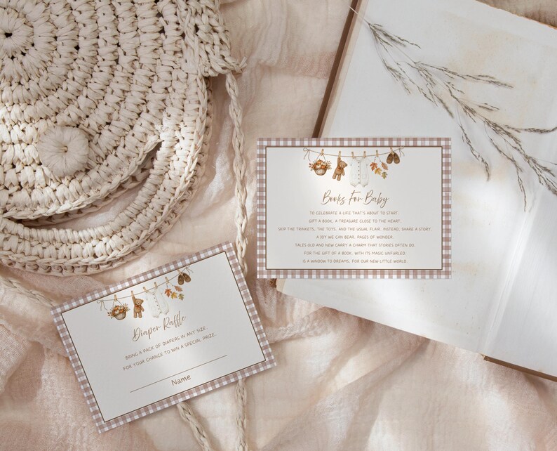 May include: Two rectangular cards with a light brown gingham border. The top card features a clothesline illustration with baby items and the text Books For Baby. The bottom card features a similar clothesline illustration and the text Diaper Raffle.