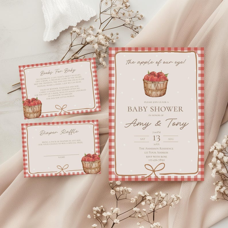 May include: A baby shower invitation set featuring a red and white gingham border, white polka dots on a cream background, and a watercolor illustration of a wooden basket filled with red apples. The text includes "The apple of our eye!", "Books For Baby", and "Diaper Raffle" with event details for Amy and Tony.