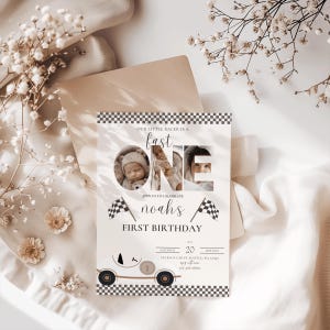 May include: A white and black checkered birthday invitation with a photo of a baby in a race car themed design. The invitation says "Our little racer is a fast one" and "Join us to celebrate Noah's first birthday".