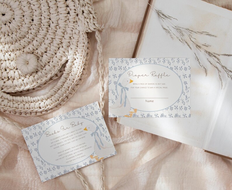 May include: Two baby shower game cards with a blue and white floral pattern. The first card says "Books for Baby" and the second card says "Diaper Raffle".