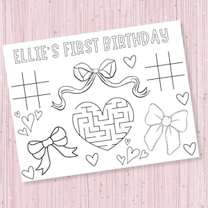 May include: A black and white printable activity sheet with the text "Ellie's First Birthday" at the top. The sheet features a heart-shaped maze, a tic-tac-toe board, and several bows.