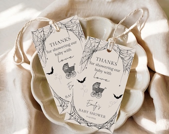 May include: Two beige baby shower gift tags with black spiderweb and bat illustrations. The tags read "THANKS for showering our baby with Love" and "Emily's BABY SHOWER 9-24-2024". Each tag has a string for hanging.