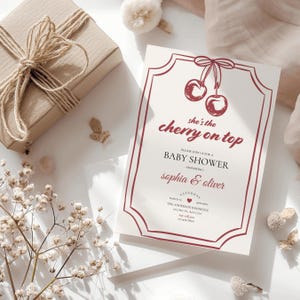 Op de afbeelding: Een rode en witte babyborrel uitnodiging met een kers op de top ontwerp. De uitnodiging luidt "She's the cherry on top" en bevat de namen "Sophia & Oliver".