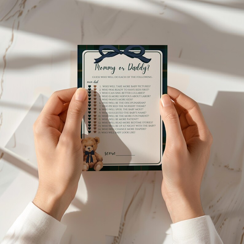 May include: A baby shower game card with the text "Mommy or Daddy?" on a green plaid background. The card includes a list of questions and a space for scoring. A small teddy bear is at the bottom.
