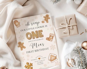 May include: A light pink and gold gingerbread-themed first birthday party invitation with the text "Oh snap our little cookie is one. Join us to celebrate Mia's first birthday."  The invitation includes a gingerbread man, a gingerbread house, a stocking, and a snowflake.