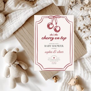 Op de afbeelding: Een witte baby shower uitnodiging met een rode kers afbeelding en de tekst "she's the cherry on top". De uitnodiging bevat de tekst "Kom gezellig met ons mee naar een baby shower ter ere van Sophia & Oliver".
