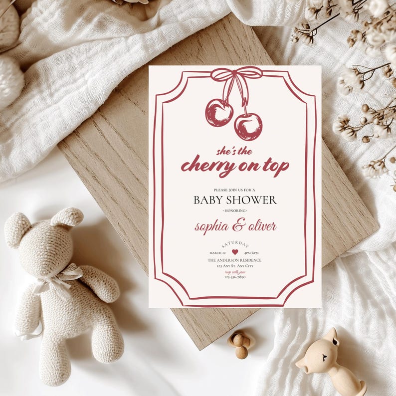 Op de afbeelding: Een witte baby shower uitnodiging met een rode kers afbeelding en de tekst "she's the cherry on top". De uitnodiging bevat de tekst "Kom gezellig met ons mee naar een baby shower ter ere van Sophia & Oliver".