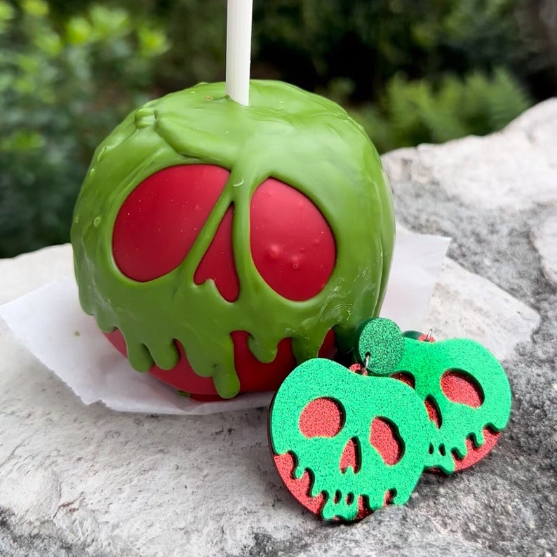 May include: A green and red candy apple with a skull design, and a pair of green and red skull-shaped earrings.