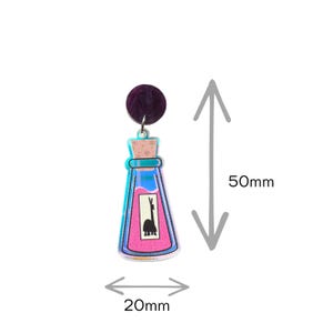 May include: A pair of earrings featuring a purple stud and a potion bottle design. The bottle is 20mm wide and 50mm long, with a pink liquid and a llama illustration. The bottle has blue and teal accents.