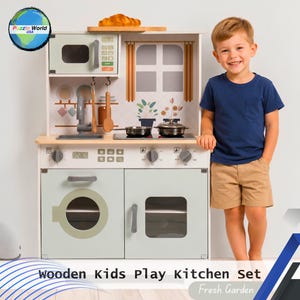 May include: Wooden kids' play kitchen set in white and light green. Features a microwave, oven, stove, sink, and various cooking utensils. Includes the text "Wooden Kids Play Kitchen Set Fresh Garden". A young boy stands next to the kitchen.