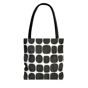 May include: Black and white tote bag with a geometric pattern of rounded squares. The bag has black handles.