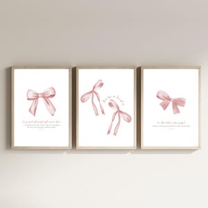 Pode incluir: Três impressões de arte imprimíveis com laços cor-de-rosa e citações inspiradoras. A primeira impressão diz "Todo bom e perfeito presente vem de cima." A segunda impressão diz "Você é tão amado." A terceira impressão diz "Por esta criança nós oramos."