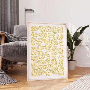 Pode incluir: Uma impressão de arte de parede retangular com um padrão repetitivo de pedaços de queijo amarelo com buracos num fundo branco. A impressão está emoldurada numa moldura de madeira clara e exibe várias formas e tamanhos de queijo.