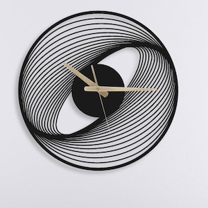 Peut inclure: Une horloge murale circulaire noire moderne avec un design tourbillonnant unique. L'horloge présente des aiguilles dorées et un centre noir. L'horloge est fixée sur un mur blanc au-dessus d'un lit gris avec des oreillers blancs et une couette blanche.