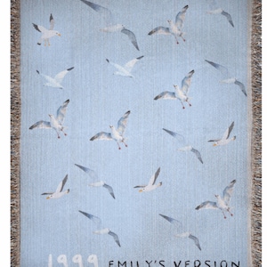 May include: A blue woven tapestry with a white background featuring a repeating pattern of seagulls flying in different directions. The tapestry has a fringe border and the text "1999 Emily's Version" at the bottom.