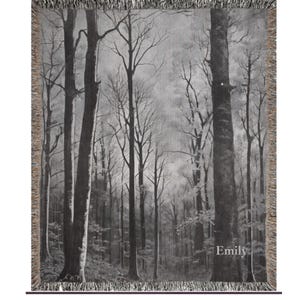 May include: Black and white woven tapestry featuring a forest scene with tall trees and a misty background. The tapestry has a fringe border and the word "Emily" is printed in the bottom right corner.