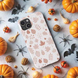 May include: A white iPhone case with a fall-themed design featuring brown, orange, and white leaves. The case has a camera cutout and a textured surface.
