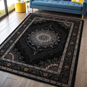 May include: A rectangular black area rug with an ornate, traditional design. The rug features a central medallion with floral and geometric patterns in shades of gray, beige, and blue. A detailed border frames the central design, adding to the rug's elegance.