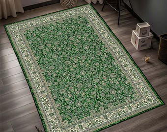 May include: A rectangular green area rug with an ornate floral pattern and a cream-colored border. The rug is placed on a dark wood floor, and the design features a central field of green with detailed floral motifs.