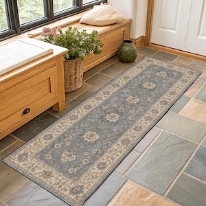 May include: A rectangular runner rug featuring a dusty blue center field adorned with a repeating cream and beige floral pattern, enclosed by a wide, intricate border in matching neutral tones with a dark, defined edge finish.