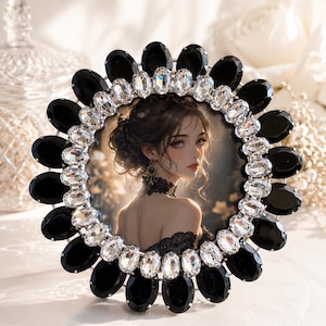 May include: A circular picture frame featuring a decorative border of alternating large black oval stones and smaller clear faceted crystals. The frame holds a portrait of a person with dark hair in an updo, wearing a black lace choker and top.