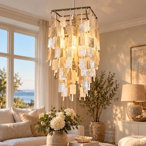 May include: A square chandelier featuring multiple tiers of translucent, rectangular shell-like panels suspended from a dark metal frame. The light fixture emits a warm, soft glow, with the individual panels creating a layered, cascading effect.