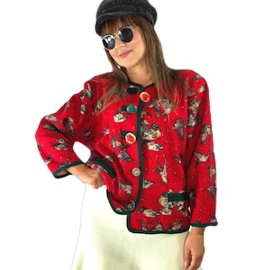 May include: A red long-sleeved jacket featuring a repeating pattern of ducks, accented with dark green trim along the edges and front closure. The jacket includes five decorative buttons down the front and is paired with a plain off-white skirt.