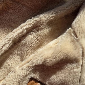 Shearling Original label confirming genuine sheepskin, European craftsmanship, beige wool texture.