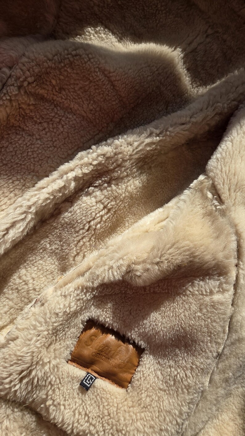 Shearling Original label confirming genuine sheepskin, European craftsmanship, beige wool texture.