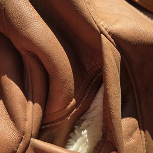 Pocket detail with wool trim and soft plush lining, handmade beige sheepskin jacket, warm and elegant outerwear.