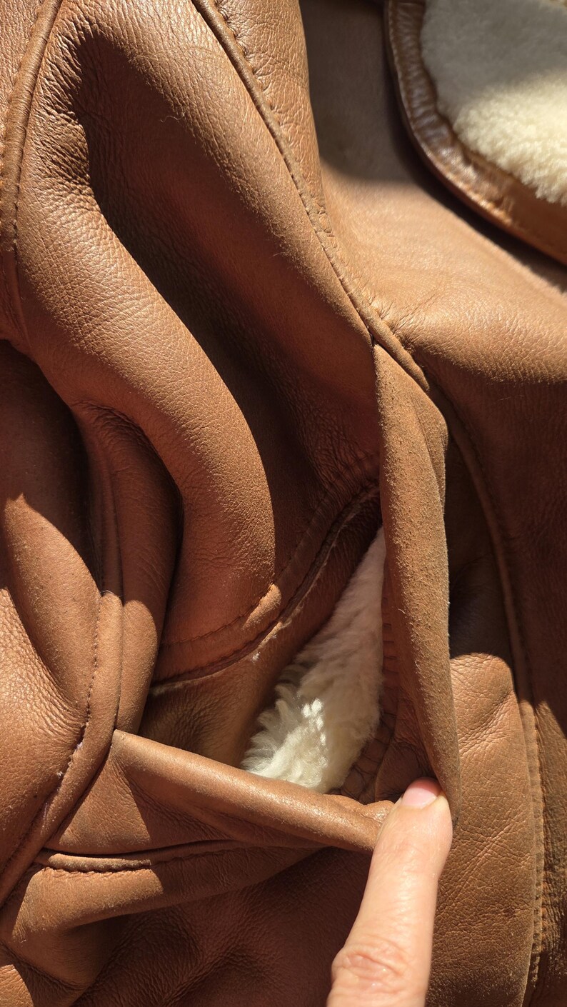 Pocket detail with wool trim and soft plush lining, handmade beige sheepskin jacket, warm and elegant outerwear.