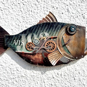 Peut inclure: Sculpture de poisson de style steampunk avec une finition métallique. Le poisson présente des engrenages, des rivets et d'autres éléments mécaniques. La queue et la nageoire dorsale sont en bois. Le mot "VIS" est visible.