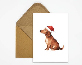 May include: A watercolor illustration of a brown dachshund wearing a red and white Santa hat, sitting on a white card. The card is next to a brown envelope, perfect for holiday greetings.