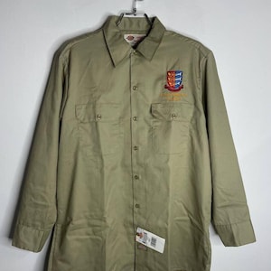 May include: A khaki long-sleeve work shirt with a button-down collar and two chest pockets. The shirt has an embroidered patch on the left chest that says "Environmental Health & Safety".