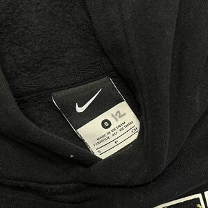 May include: Black hooded sweatshirt with a white Nike logo and size tag. The tag reads "S" and "Made in Vietnam, Fabrique au Vietnam".