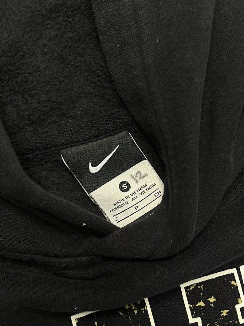 May include: Black hooded sweatshirt with a white Nike logo and size tag. The tag reads "S" and "Made in Vietnam, Fabrique au Vietnam".