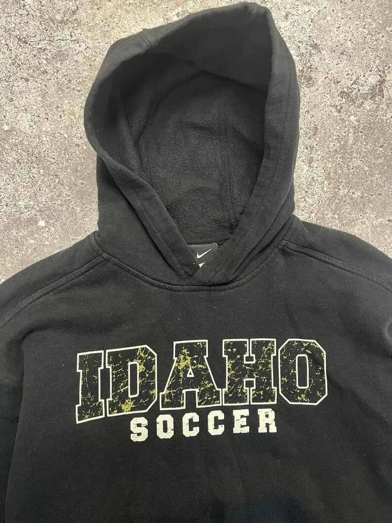 May include: Black hooded sweatshirt with a distressed white and yellow graphic that says "IDAHO SOCCER".