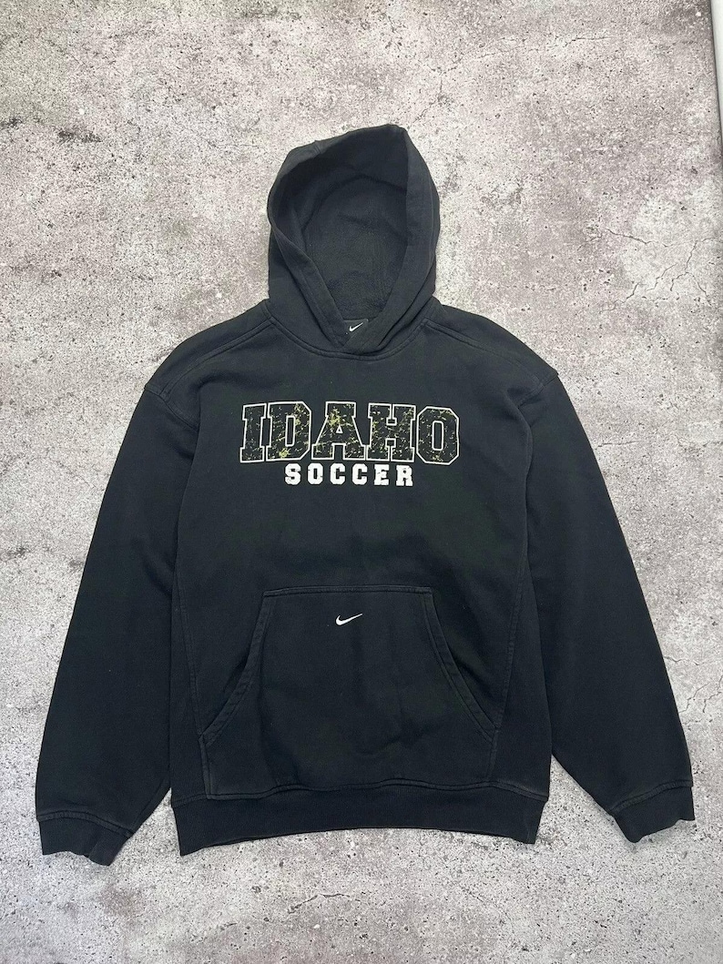 May include: Black hooded sweatshirt with a white "IDAHO SOCCER" graphic on the front. The sweatshirt has a white Nike swoosh logo on the left chest and a white Nike swoosh logo on the front pocket.