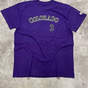 May include: Purple t-shirt with "COLORADO" and the number "3" printed on the front in white.