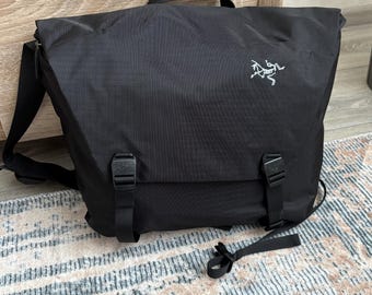 Bolso bandolera Arc'teryx negro vintage, impermeable, estilo técnico, minimalista, para viajes al aire libre y para portátil.
