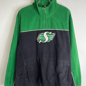 May include: Green and black fleece pullover with a high collar and a quarter-zip closure. The front features a white and black logo. The sleeves are green, and the lower half of the garment is black. A white stripe separates the green and black sections.