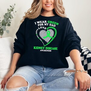 May include: Black sweatshirt with a green ribbon and the text "I wear green for my dad love hope & never give up kidney disease awareness" on the front.