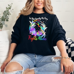 May include: Black sweatshirt with a rainbow hummingbird design and the text "In This Family No One Fights Alone".