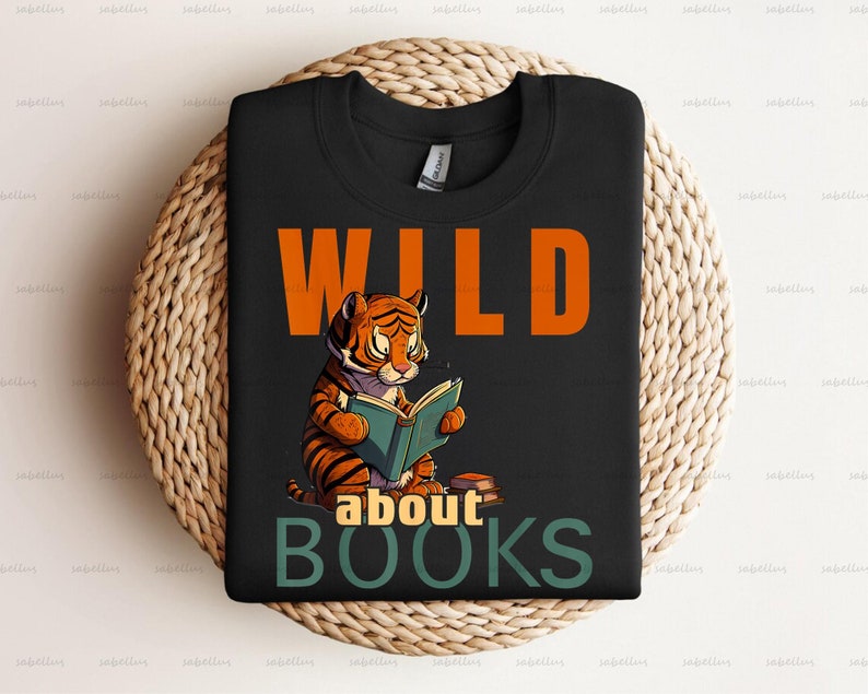 Pu&ograve; includere: Maglietta nera con una tigre di cartone animato che legge un libro. Il testo "WILD about BOOKS" &egrave; stampato sulla maglietta.