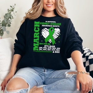 May include: A black sweatshirt with a green ribbon and the text "IS NATIONAL KIDNEY DISEASE AWARENESS MONTH MARCH BUT FOR ME IT'S ALSO JAN, FEB, APR, MAY, JUN JUL, AUG, SEP, OCT, NOV & DEC"