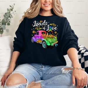 May include: A black sweatshirt with a colorful truck and the text "Loads of Love" printed on the front. The truck is decorated with flowers and a rainbow ribbon.